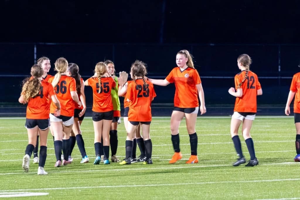 Youth soccer team in orange uniforms on field