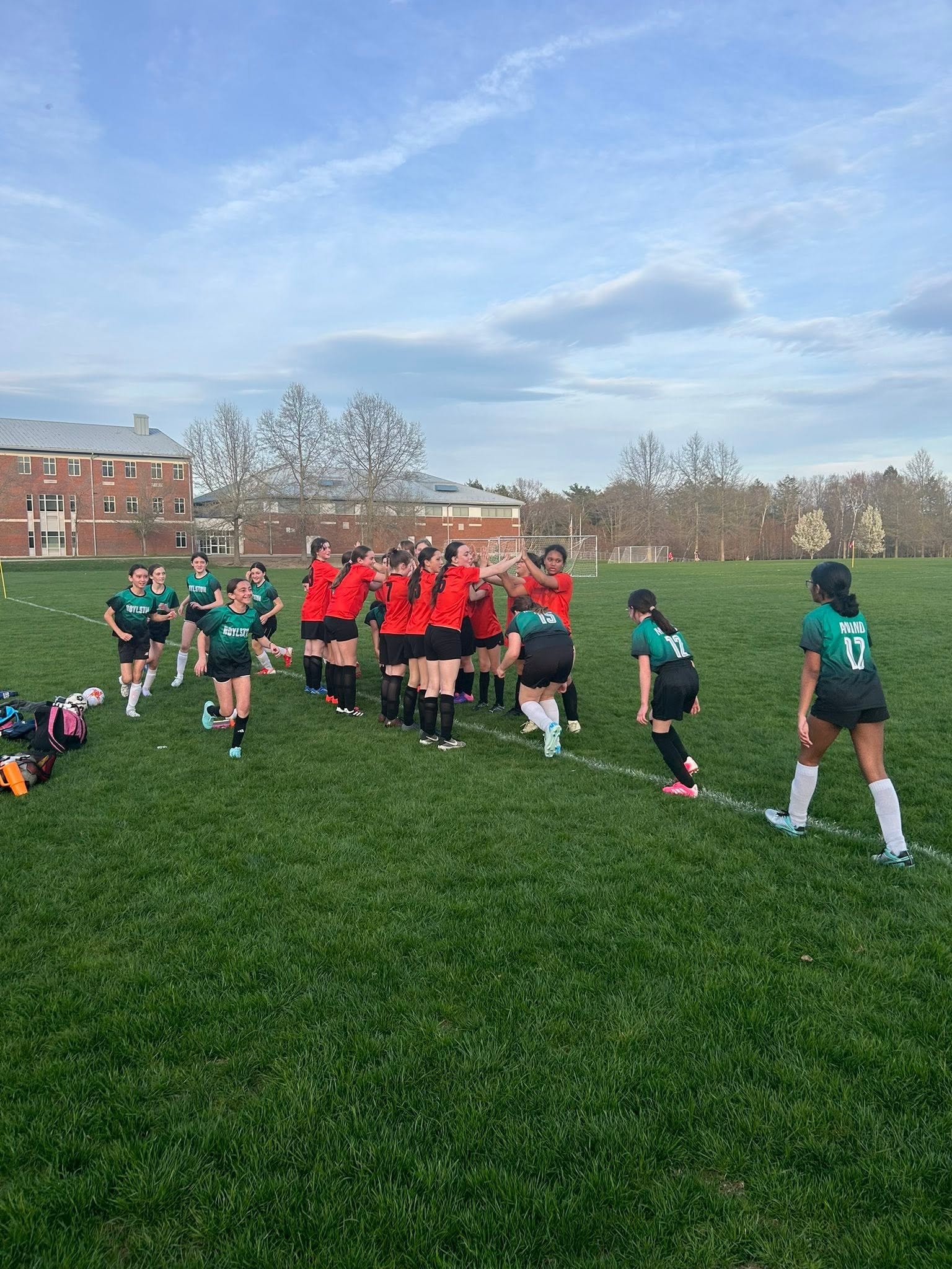 Girls soccer teams high-fiving on field