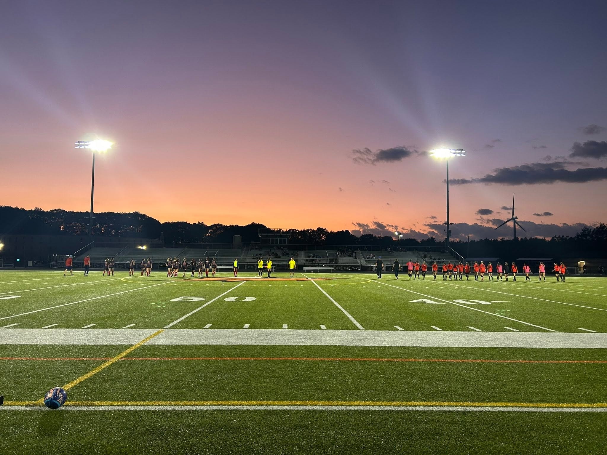 Soccer teams lined up on field at dusk