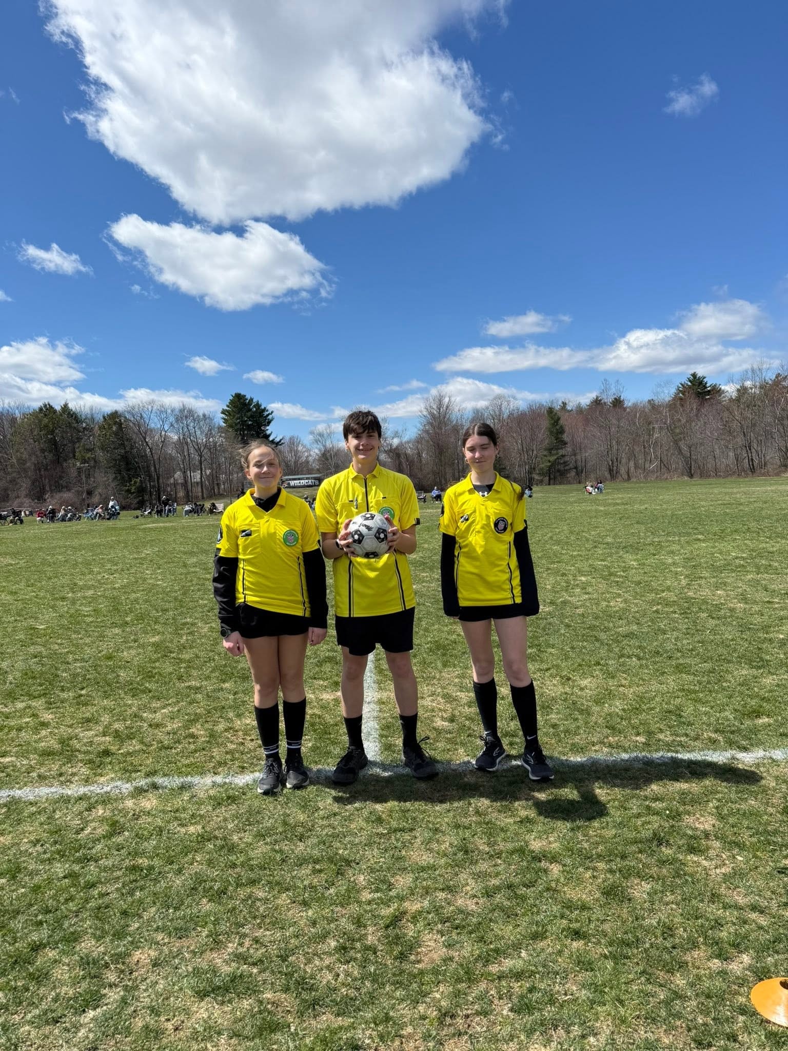 Young soccer referees holding ball on field